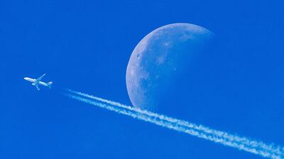 An aircraft passes the setting moon over Frankfurt, Germany. Michael Probst / AP Photo