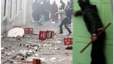 A Tunisian riot policeman takes shelter behind a door while protesters throw stones during clashes in Tunis January 28, 2011. Tunisian riot police on Friday destroyed the makeshift camp set up by anti-government protesters outside the prime minister's office, while Islamists marched through central Tunis demanding religious freedom.