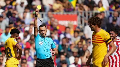 Referee Jose Maria Sanchez Martinez shows a yellow card to Barcelona's Marcos Alonso. AP