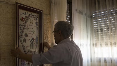 For Mr Al Mahdi, living in view of the Western Wall was a special part of growing up. The wall, sacred to Jews as a remnant of the retaining wall of the Second Jewish Temple, which was destroyed by the Romans in 70AD, is also a religious place for Muslims. Here, he is hanging a framed map of Palestine that consists of tiny embroidery stitches, handmade by his wife. Photo by Heidi Levine for The National
