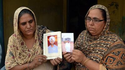 Sukhwinder Kaur, left, and Ranjit Kaur show photographs of their sons Manjinder Singh and Jatinder Singh respectively, who are among 40 Indian workers missing in Iraq, at their village about 30km from Amritsar in India's Punjab state. Raminder Pal Singh / EPA / 18 June, 2014.