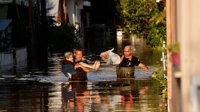 A firefighter carries an elderly woman through floodwaters after torrential rain in Larissa, Greece. Reuters