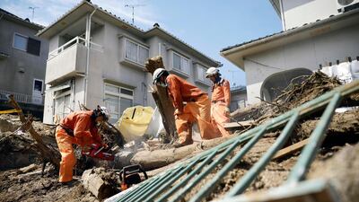 Rescuers cut driftwood to remove it from a residential area after flooding caused by heavy rains in Kumano town, Hiroshima prefecture, southwestern Japan, on Thursday, July 12. Kyodo News via AP