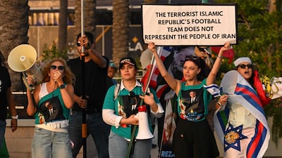 People hold pre-revolutionary Iranian flags as they protest the Iranian regime outside Carson Sports Park before Iran’s training session in Los Angeles on June 14, 2026. AFP