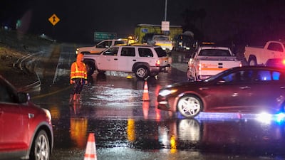 A CalTrans worker directs traffic at a motorway entrance. The 101 motorway is closed near Montecito. AP