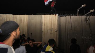 An Iraqi protester waves the Iraqi national flag as he stands on a concrete wall at the Iranian counsulate in Karbala, Iraq, 03 November 2019. EPA