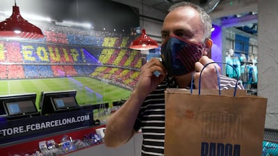 A supporter poses wearing a mask bearing the logo of FC Barcelona after buying it at the FC Barcelona. AFP