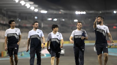 Yuki Tsunoda of Japan and Scuderia AlphaTauri team members walk the track at Yas Marina. Getty