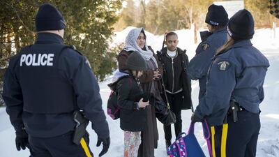 Royal Canadian Mounted Police officers arrest an asylum claimant and her two daughters after they crossed the border into Canada from the United States on March 17, 2017, near Hemmingford, Quebec. Paul Chiasson / The Canadian Press via AP