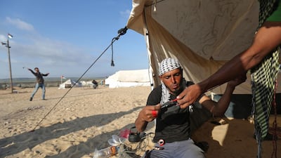 A man prepares a slingshot as Palestinians prepare to demonstrate along the border with the Gaza strip, east of Jabalia. Mohammed Abed / AFP