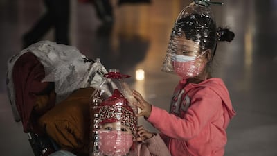 Chinese children wear plastic bottles as makeshift homemade protection and protective masks while waiting to check in to a flight at Beijing Capital Airport on January 30, 2020 in Beijing, China. The number of cases of a deadly new coronavirus rose to over 7,000 in mainland China on Thursday. Getty