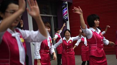 Employees of a beauty salon exercise together outside their shop in Beijing. How Hwee Young / EPA