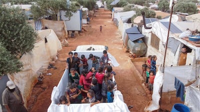 SYRIA: An aerial picture shows Syrian youths playing in a mobile makeshift pool set-up with a tarpaulin in the back of a lorry amid the heat, at a camp for the internally displaced near the village of Killi in the north of the northwestern Idlib province, on May 22, 2020, ahead of the Eid al-Fitr feast marking the end of the Muslim holy month of Ramadan. AFP