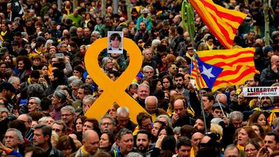 Protesters hold a yellow ribbon with a picture of Catalonia's deposed leader Carles Puigdemont while waving Catalan pro-independence Estelada flags during a demonstration in Barcelona, Spain, on March 25, 2018. Lluis Gene / AFP Photo
