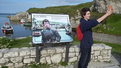 A Game of Thrones fan takes a ‘selfie’ beside a plaque at Ballintoy Harbour, which doubles as the Iron Islands in the series. Charles McQuillan / Getty Images