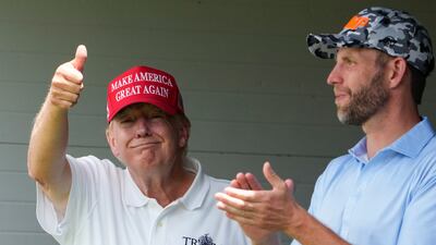 Mr Trump gives a thumbs up to fans in the crowd as he stands with his son Eric Trump. AP