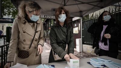 Volunteers distribute face masks outside a metro station in Vincennes, near Paris. AFP