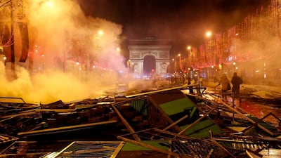 Pedestrians walk amongst extinguished burning material near The Arc de Triomphe on the Champs Elysees in Paris. AFP