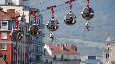 People dressed as cyclists perform suspended from cable cars before the start of the stage. EPA