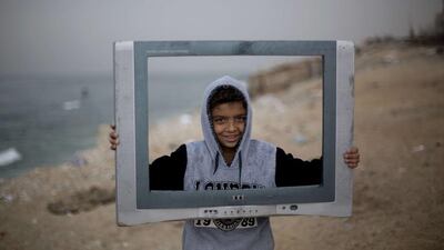 A Palestinian boy poses inside the frame of a broken television at the Al Shatee refugee camp in Gaza City. Mohammed Abed / AFP Photo