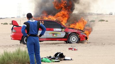 Co-driver Faris looks at their burning Mitsubishi Lancer Evolution VIII during the Kuwait International Rally in Kuwait City. AFP