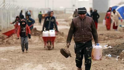 Displaced Iraqis, who fled fighting between Iraqi security forces and ISIL, walk through the mud as they bring heating fuel to their families, at a camp for internally displaced people in Khazir, near Iraq's Mosul. Hadi Mizban/AP Photo