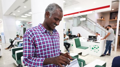 An Indian worker counts his "amnesty blessings" after learning that he can return to his family without paying thousands of dirhams in visa overstay fines after he obtains an exit pass at an Amer centre in Bur Dubai in Dubai. Victor Besa / The National