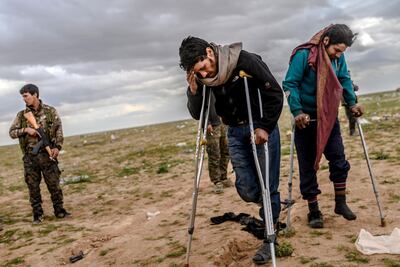 Men suspected of being ISIS fighters wait to be searched by members of the Kurdish-led Syrian Democratic Forces after leaving the group's last holdout in Baghouz, in Syria's northern Deir Ezzor province. Bulent Kilic / AFP
