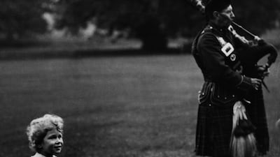 Queen Elizabeth watches members of a pipe band play in the grounds of Glamis Castle in 1929. Getty Images