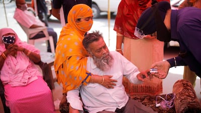 A volunteer uses a pulse oximeter to check the oxygen saturation of a man's blood before providing him oxygen support for free at a Gurudwara (Sikh temple), amidst the spread of coronavirus disease, in Ghaziabad, India. Reuters