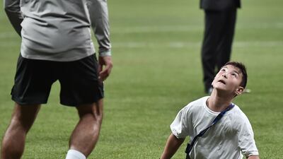 Liverpool's Egyptian midfielder Mohamed Salah plays football with a child at the end of a training session. AFP