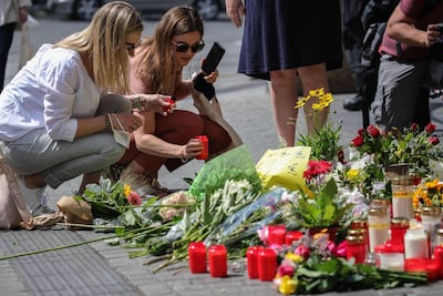 Two women place a candle at a makeshift memorial of flowers and candles in tribute to the victims of a deadly attack in Wuerzburg, southern Germany. AFP / ARMANDO BABANI