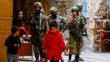 A Palestinian woman ushers her children away from a group of Israeli soldiers during a weekly settlers’ tour in Hebron, in the occupied West Bank. Reuters