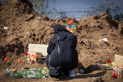 A woman mourns beside a grave at a temporary burial site in Tyre, Lebanon. Reuters