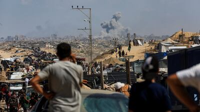Displaced Palestinians flee south as smoke rises from an Israeli strike in central Gaza on Wednesday. Reuters