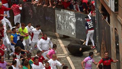 A bull falls to the ground as mozos try to avoid the bulls. EPA