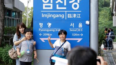A family member poses for pictures in front of a signboard showing the distance to North Korea's capital Pyongyang and to South Korea's capital Seoul from Imjingang Station in Paju, near the border with North Korea, South Korea, Sunday, Sept. 16, 2018. South Korean President Moon Jae-in is to fly to Pyongyang, North Korea, next Tuesday, Sept. 18, for a three-day trip that he says will focus on facilitating talks between the United States and North Korea and finding ways to ease a military standoff along the Koreas' heavily fortified border. (AP Photo/Ahn Young-joon)