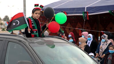 A girl waves a national flag from a car as people gather in Tripoli to celebrate. AFP