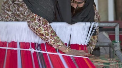 A lady weaves a traditional fabric at the Abu Dhabi Women’s Union stand. Silvia Razgova / The National