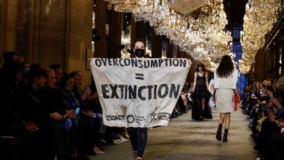 An Extinction Rebellion activist burst on to the catwalk with a banner that read: 'Overconsumption = Extinction' during Louis Vuitton's show at Paris Fashion Week. Reuters