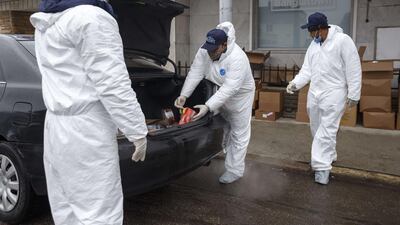Armani Asad, owner of Maa Fashion in Hamtramck (C) places donated food in the trunk of a car while Nazel Huda, left, holds open the door on the first day of Ramadan. Getty Images via AFP