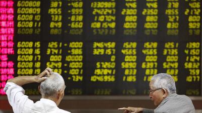 CHINA - Investors chat as they watch a board showing stock prices at a brokerage office in Beijing. Chinese shares fell in early trade before reversing course late Monday afternoon. Kim Kyung-Hoon / Reuters
