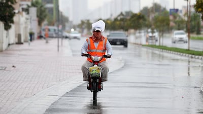 A motorcyclist rider covers his face and has a bag on his head to stay dry as the rain comes down in Dubai. Chris Whiteoak / The National