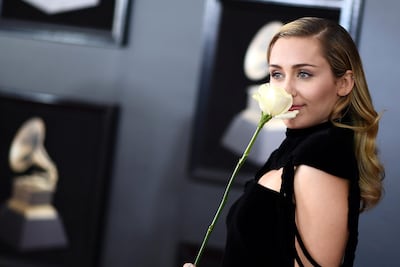 Clad in black, white rose in hand, singer Miley Cyrus makes her point for #TimesUp at the Grammys in New York. AFP