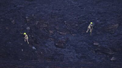 Firefighters walk across burnt moorland as they tackle a blaze above Marsden. AFP