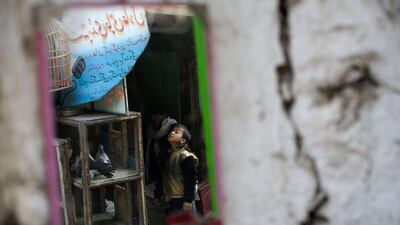 An Afghan boy is reflected in a mirror on February 25, 2014, as he looks at pigeons inside a cage at the bird market in Kabul on February 25, 2014. Afghanistan’s economy is recovering from decades of conflict. But despite an improvement in the last decade it is extremely poor, and highly dependent on foreign aid. Nicolas Asfouri / AFP photo