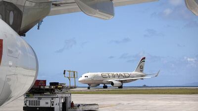 An Air Seychelles plane stands parked, undergoing servicing, as an Etihad plane taxis nearby at Victoria airport. Etihad Airways signed a deal with Seychelles government in January 2012, acquiring 40 per cent stake in Air Seychelles. Silvia Razgova / The National