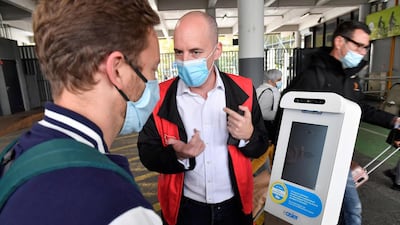 An agent helps a man taking his body temperature in front of a "health terminal" in Toulouse, France. AFP