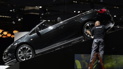 An employee stands on a ladder as he polishes the alloy wheel of a Opel convertible automobile,at the 65th Frankfurt International Motor Show in Frankfurt. Jason Alden / Bloomberg