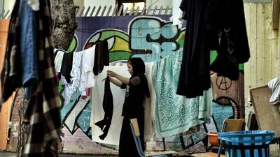 A woman dries laundry in the courtyard of an abandoned school used by volunteers for hosting refugees in Athens. Aris Messinis / AFP